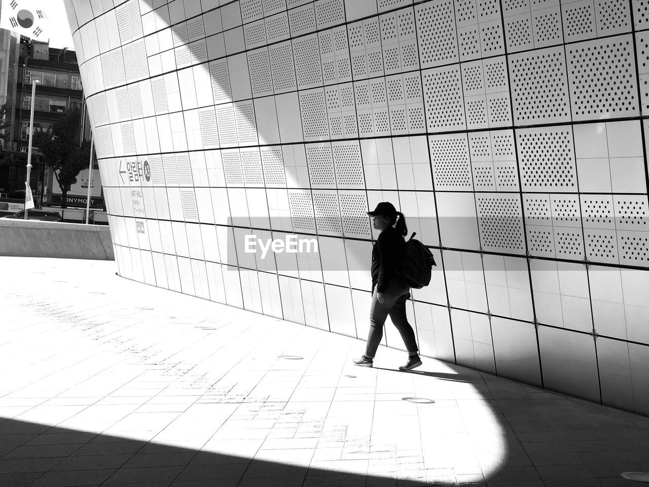 FULL LENGTH OF WOMAN WALKING ON FOOTPATH AGAINST BUILDING