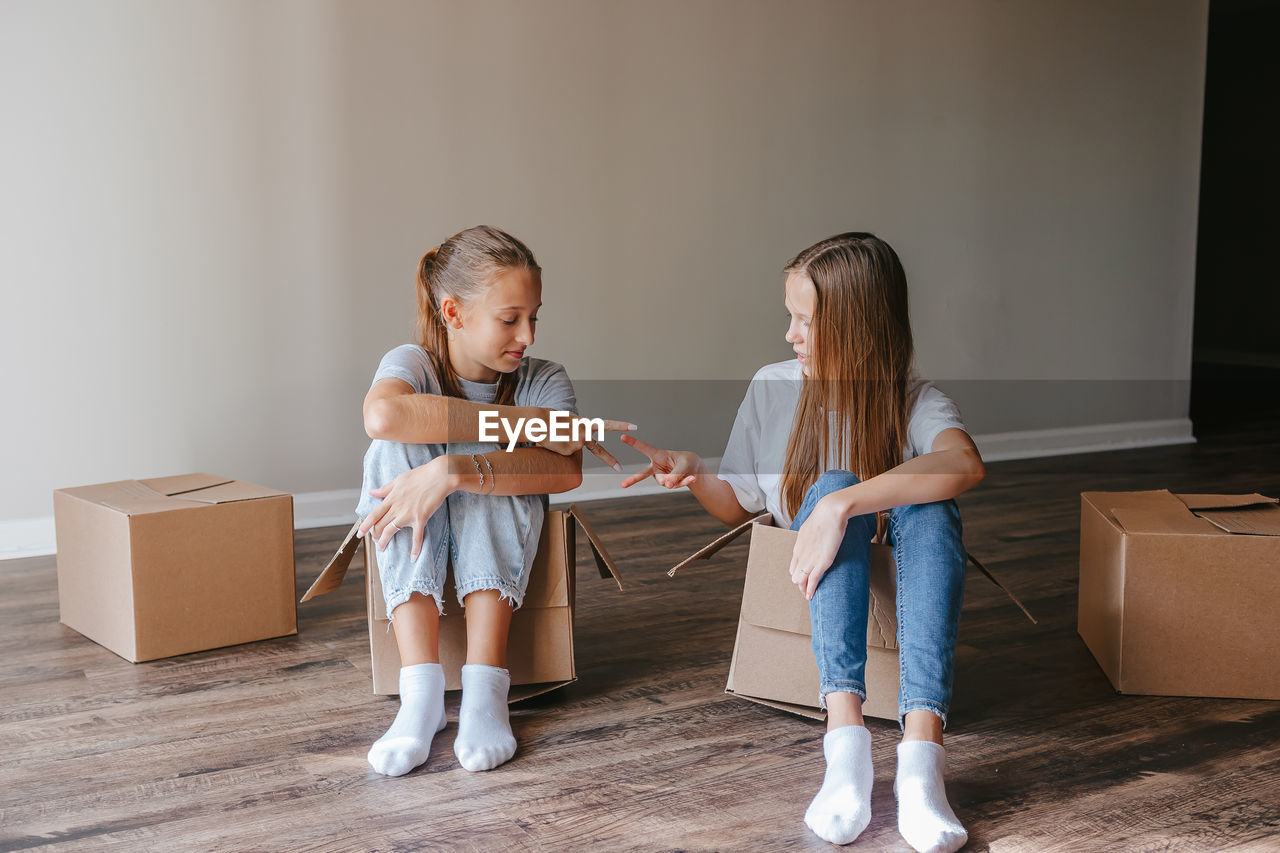 side view of mother and daughter standing against wall at home