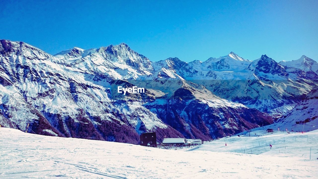 Scenic view of snowcapped mountains against clear blue sky