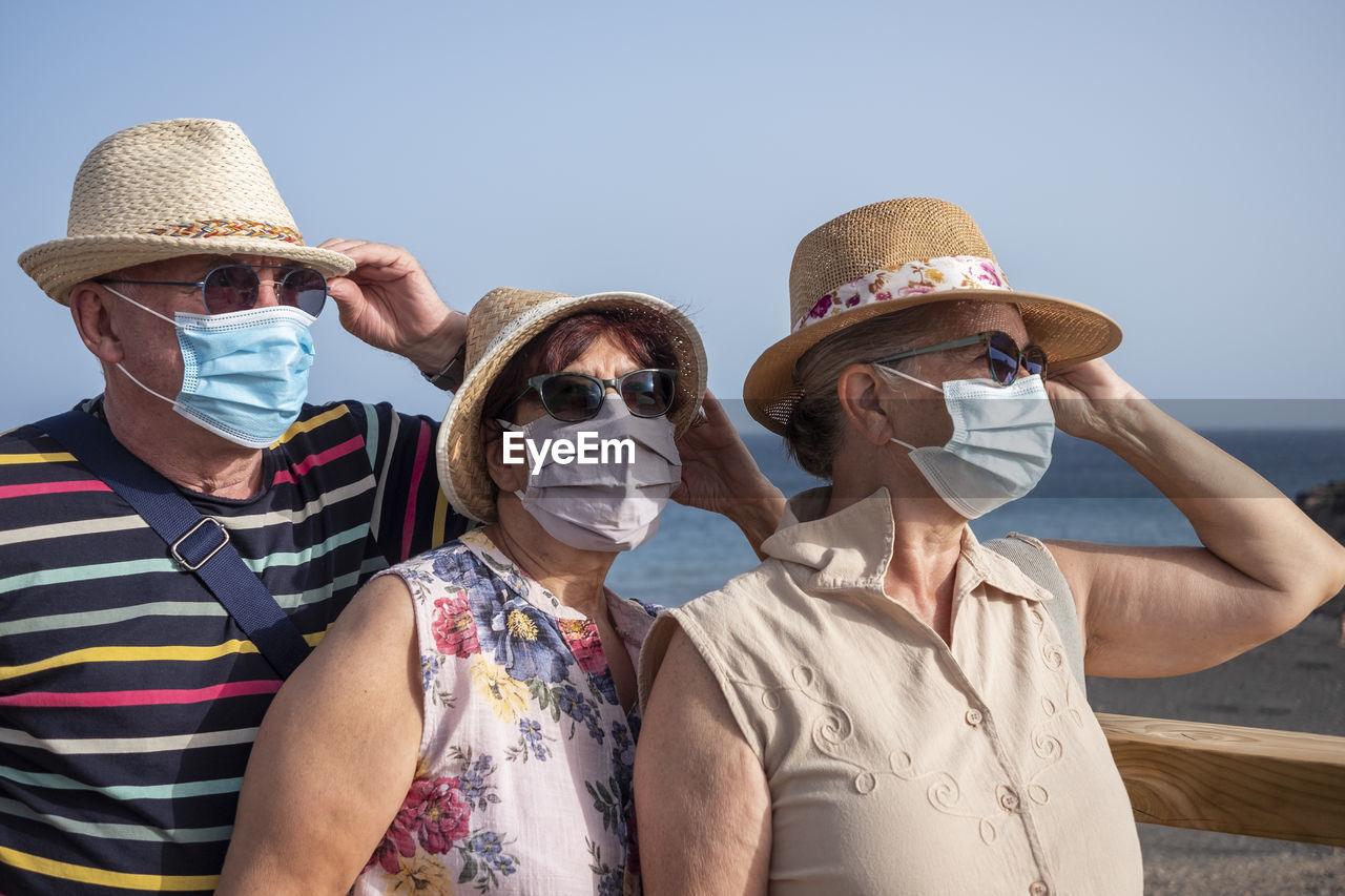 Senior friends wearing mask against sea