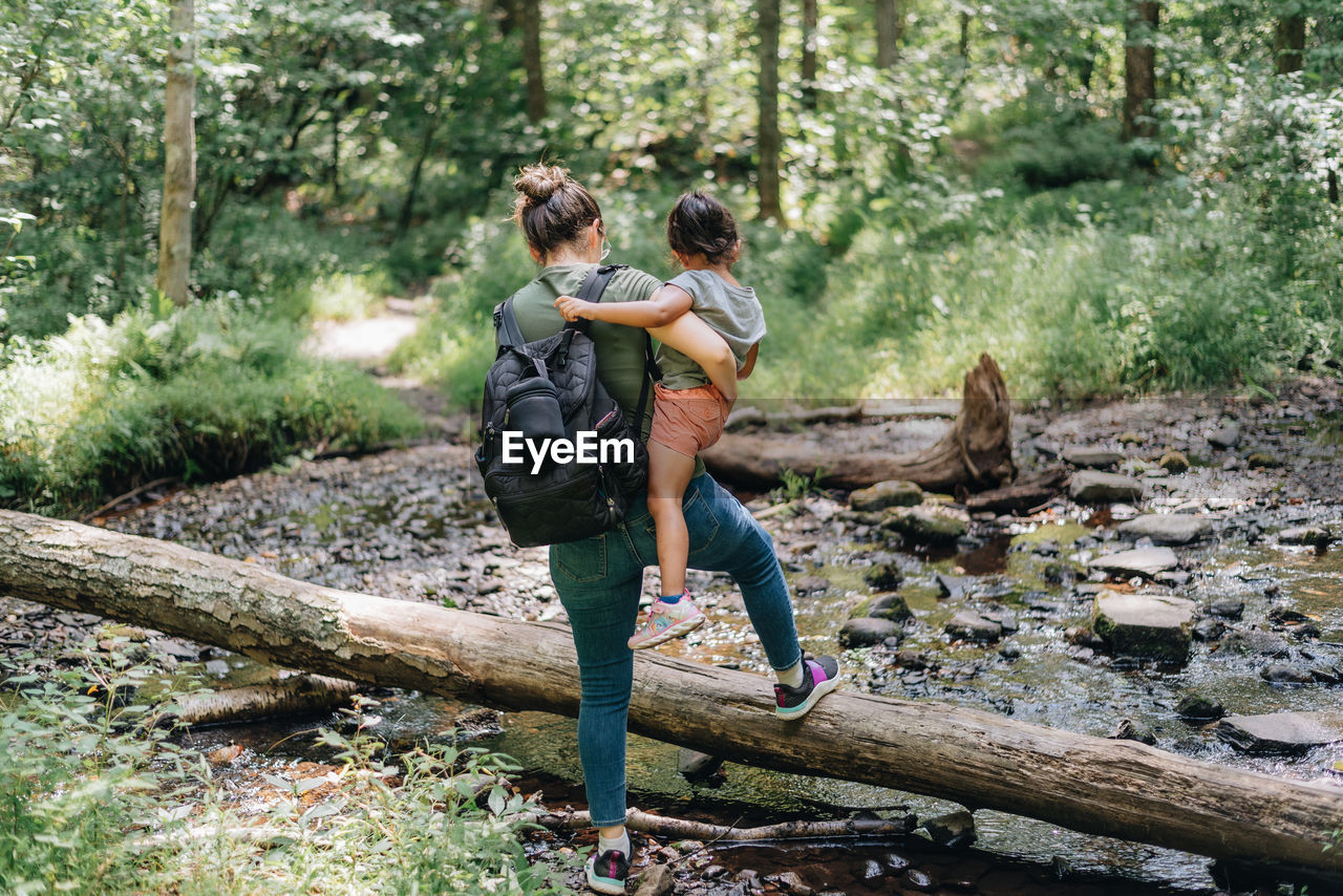 Full length of mother and daughter walking in forest