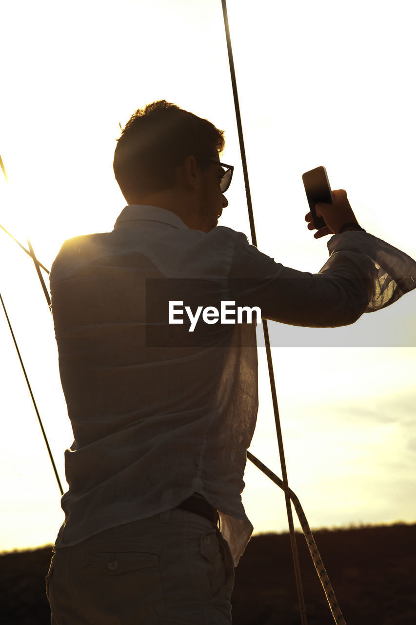 Man taking selfie while standing against sky