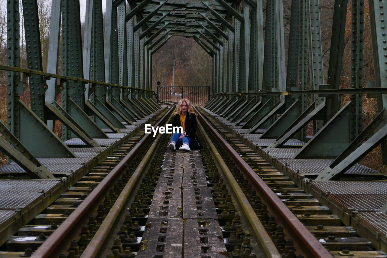 Woman sitting on railway bridge