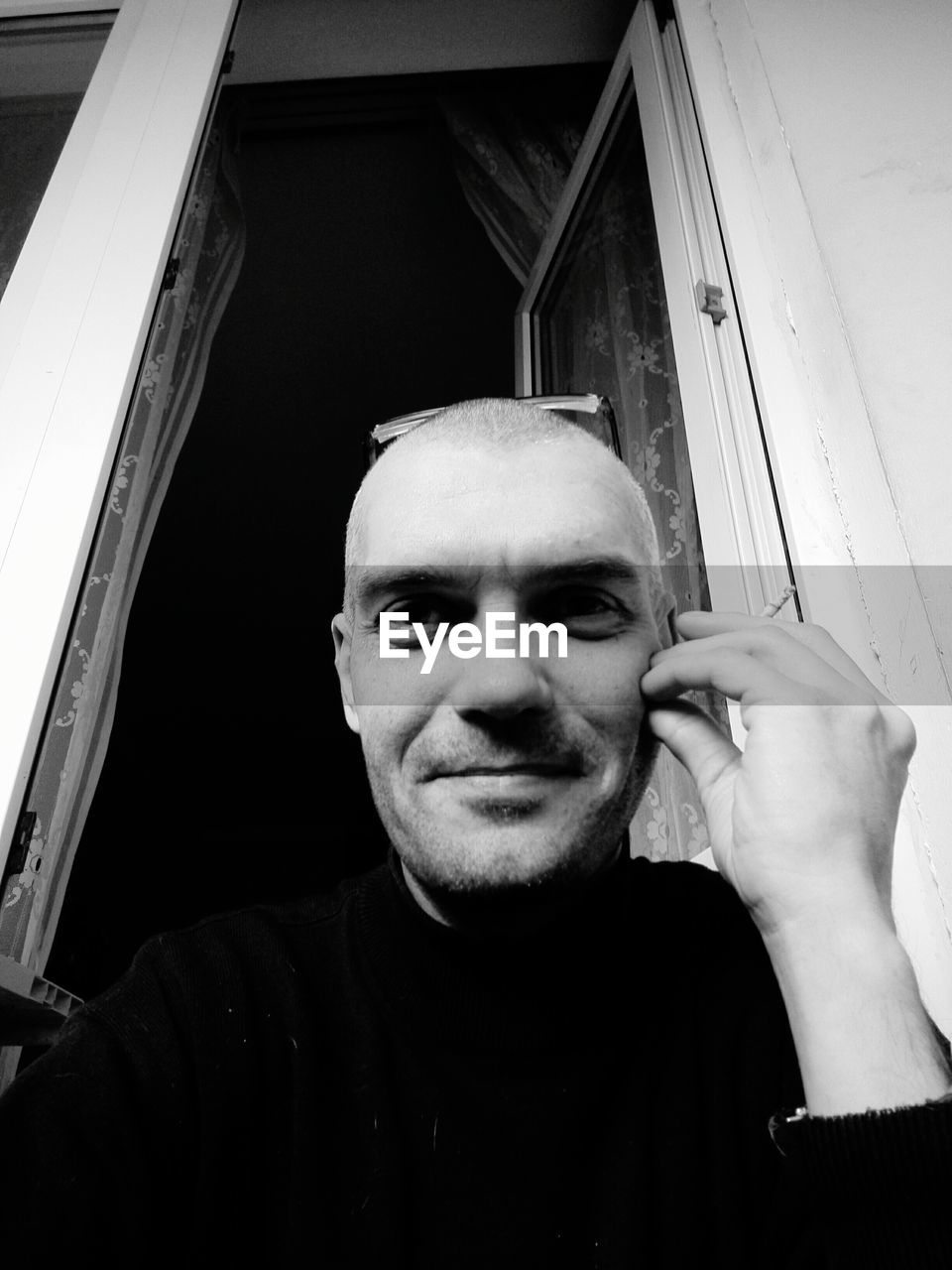 Low angle portrait of mature man sitting against window at home