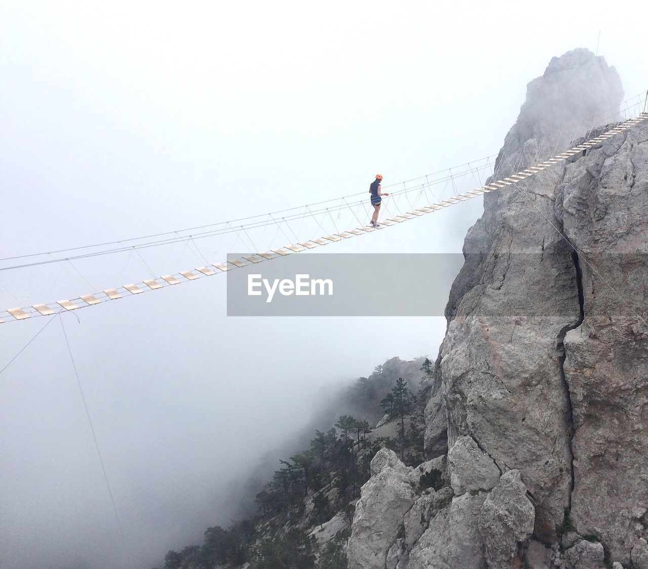 Woman on rope bridge during foggy weather