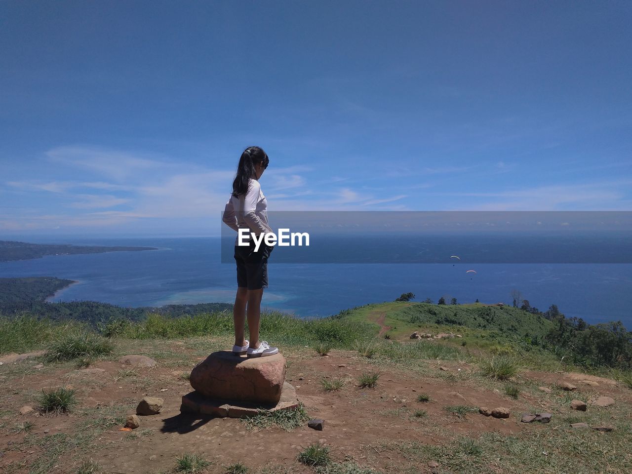 Woman on a rock with a view of the sea and blue sky