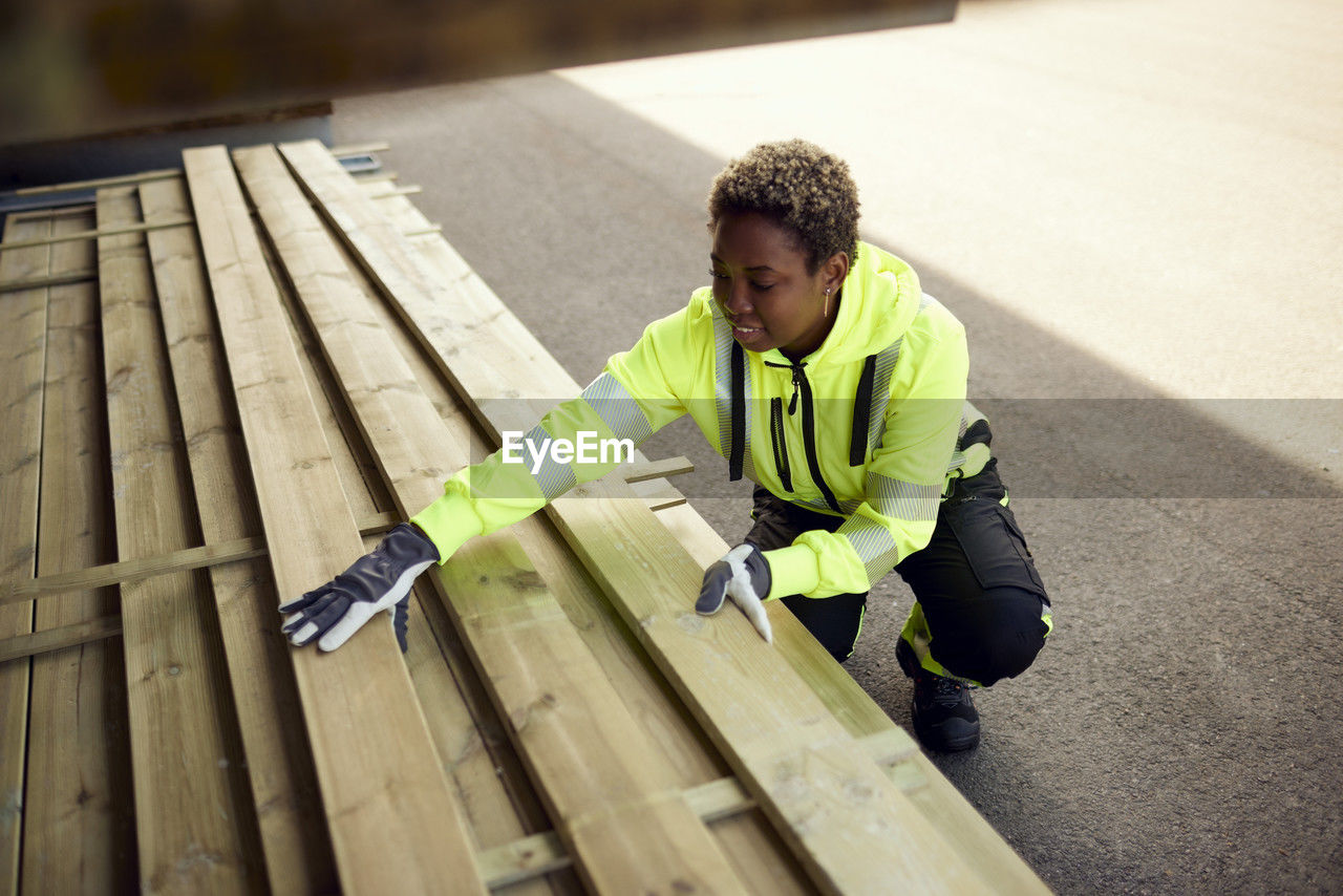 Smiling female worker arranging planks at lumber industry