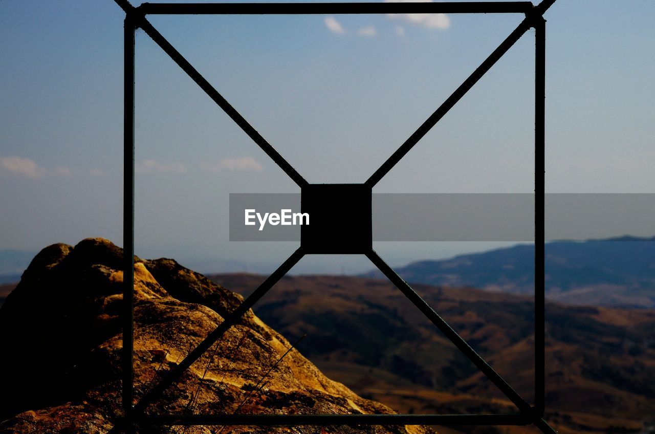 Mountains against sky seen through metal grate