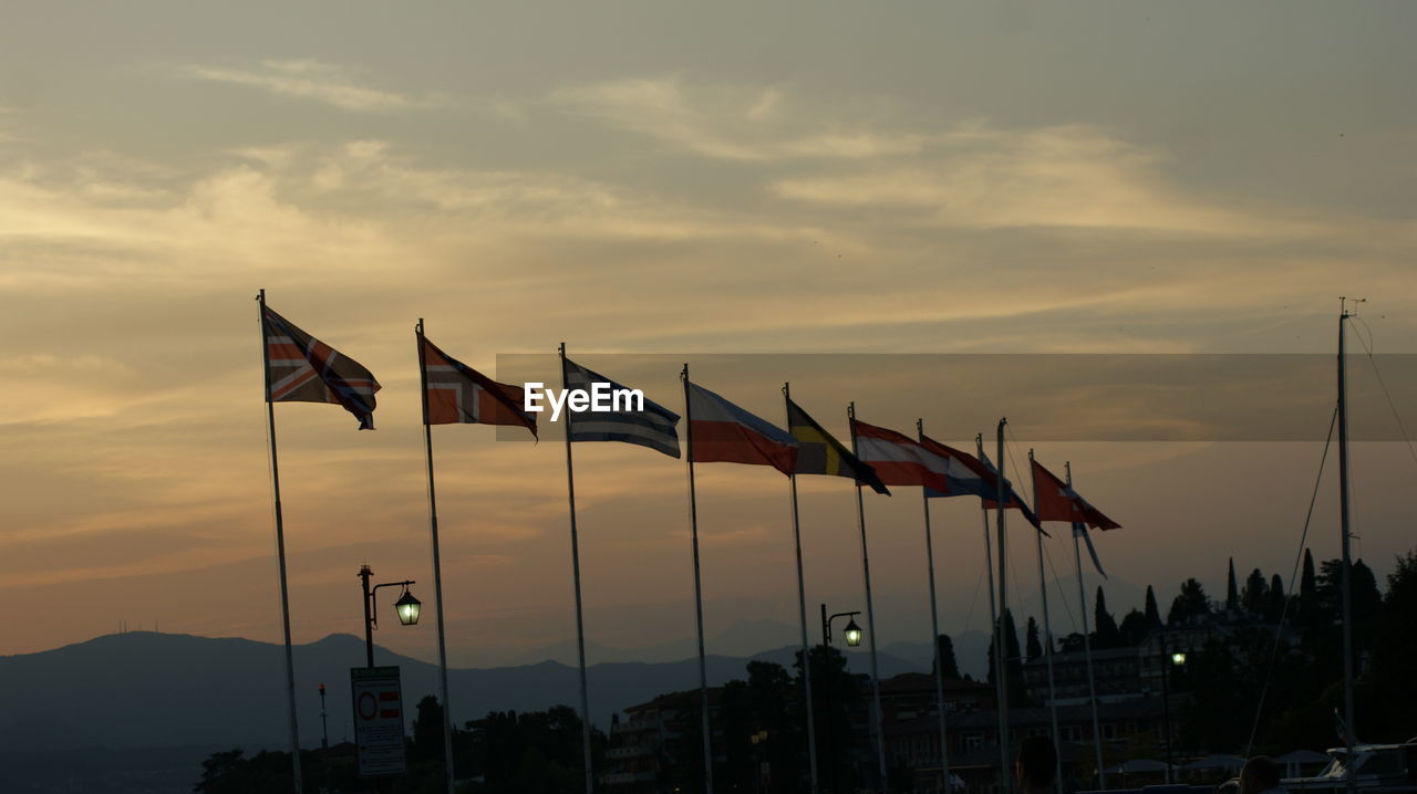 ROW OF FLAGS AGAINST SKY DURING SUNSET