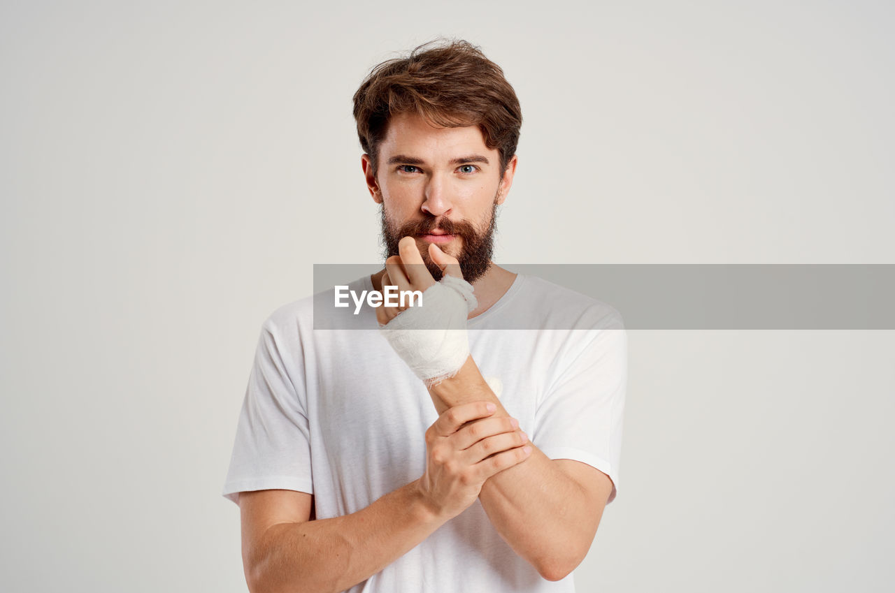 Portrait of young man standing against white background