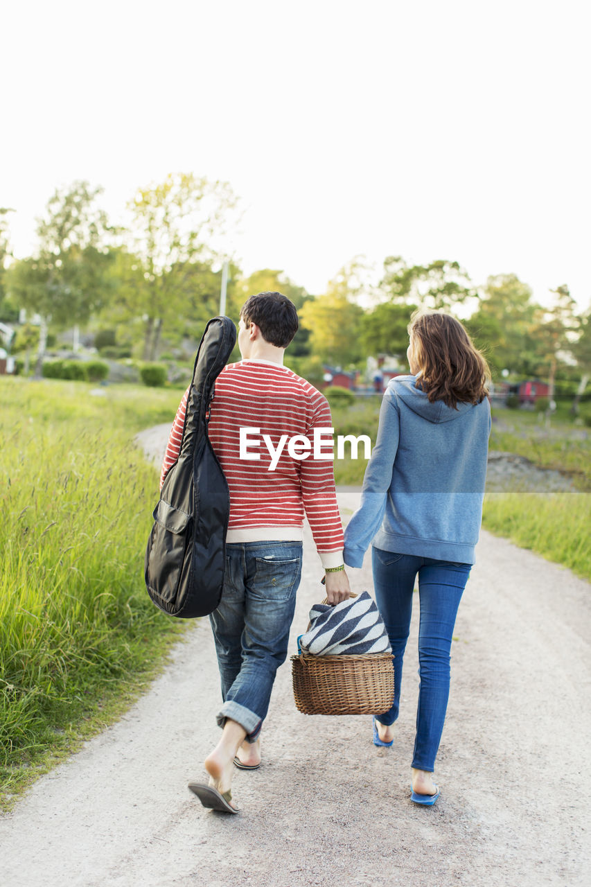 Full length rear view of couple walking on footpath in park