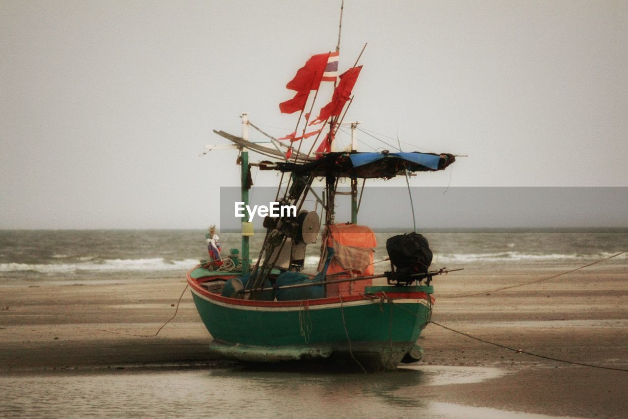 BOAT ON BEACH AGAINST CLEAR SKY