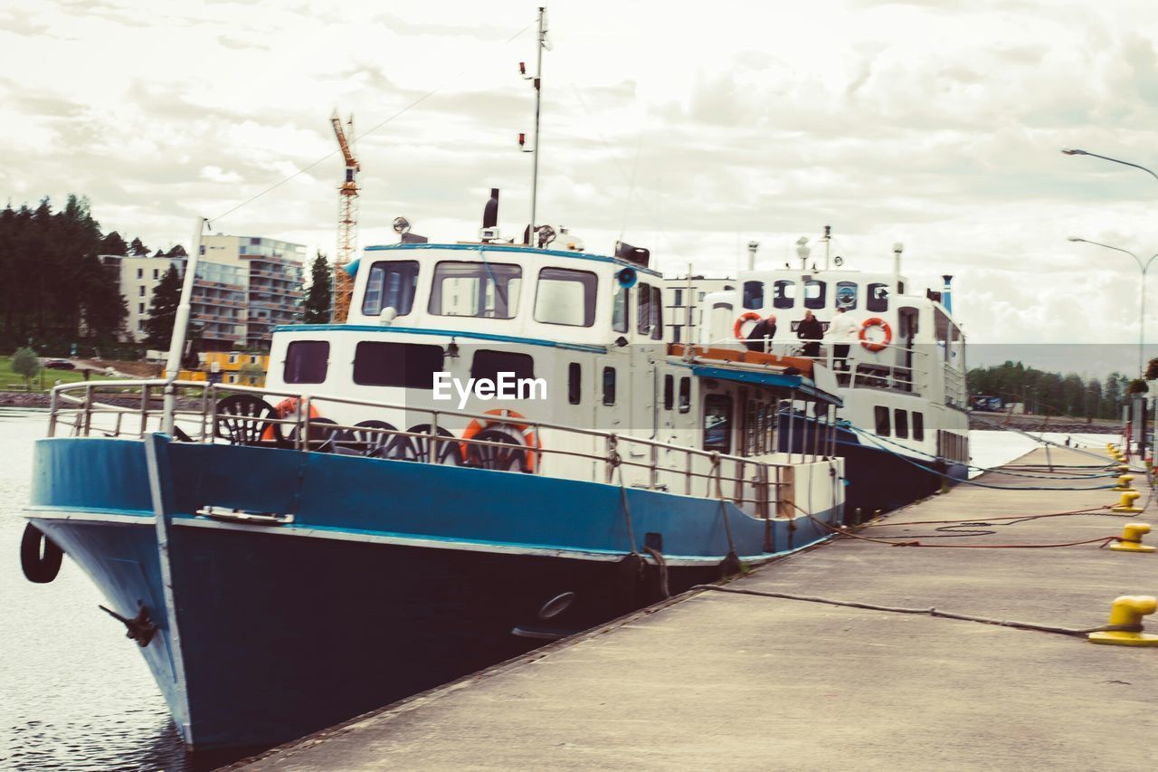 Ship moored at riverbank against sky