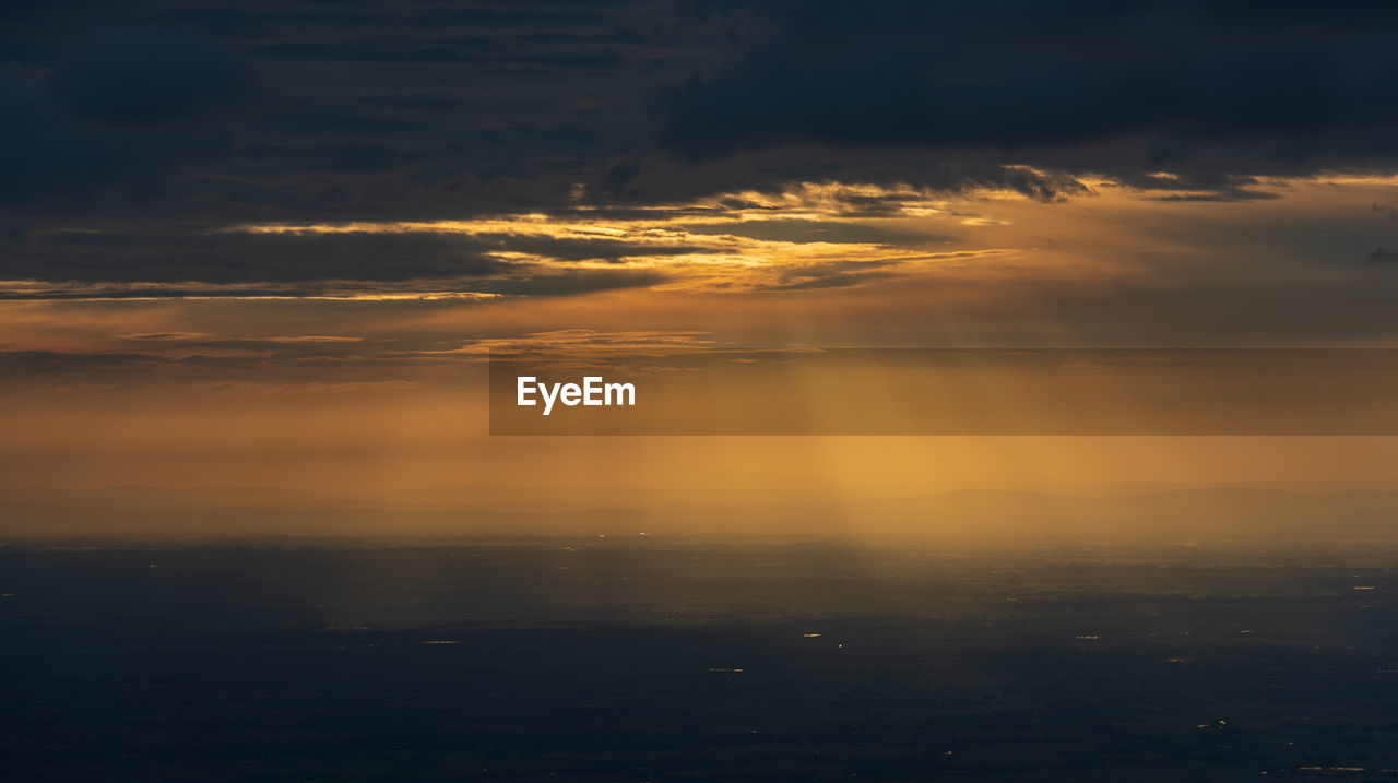 Scenic view of sea against dramatic sky during sunset