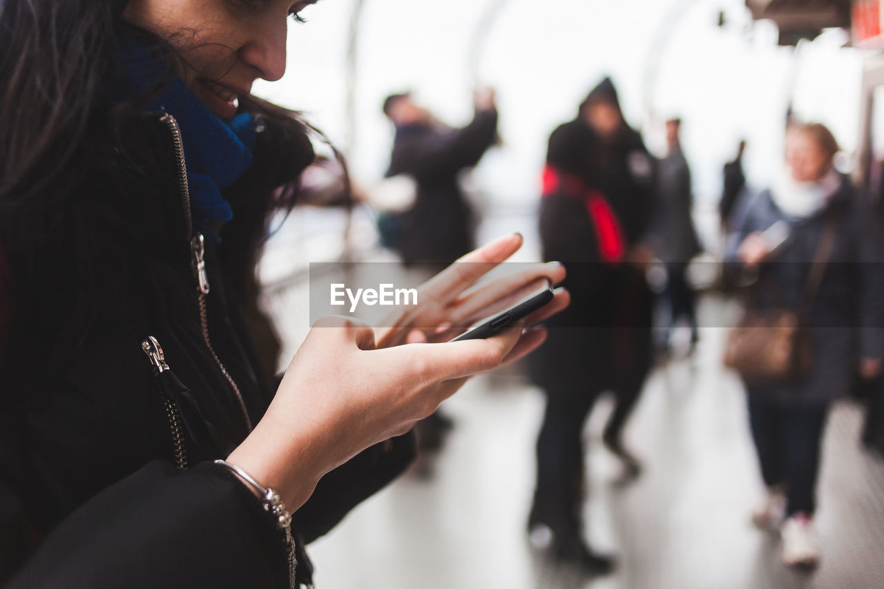 MIDSECTION OF WOMAN USING SMART PHONE