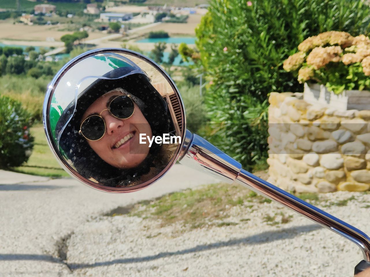 Low section of woman wearing sunglasses in a mirror of vespa scooter