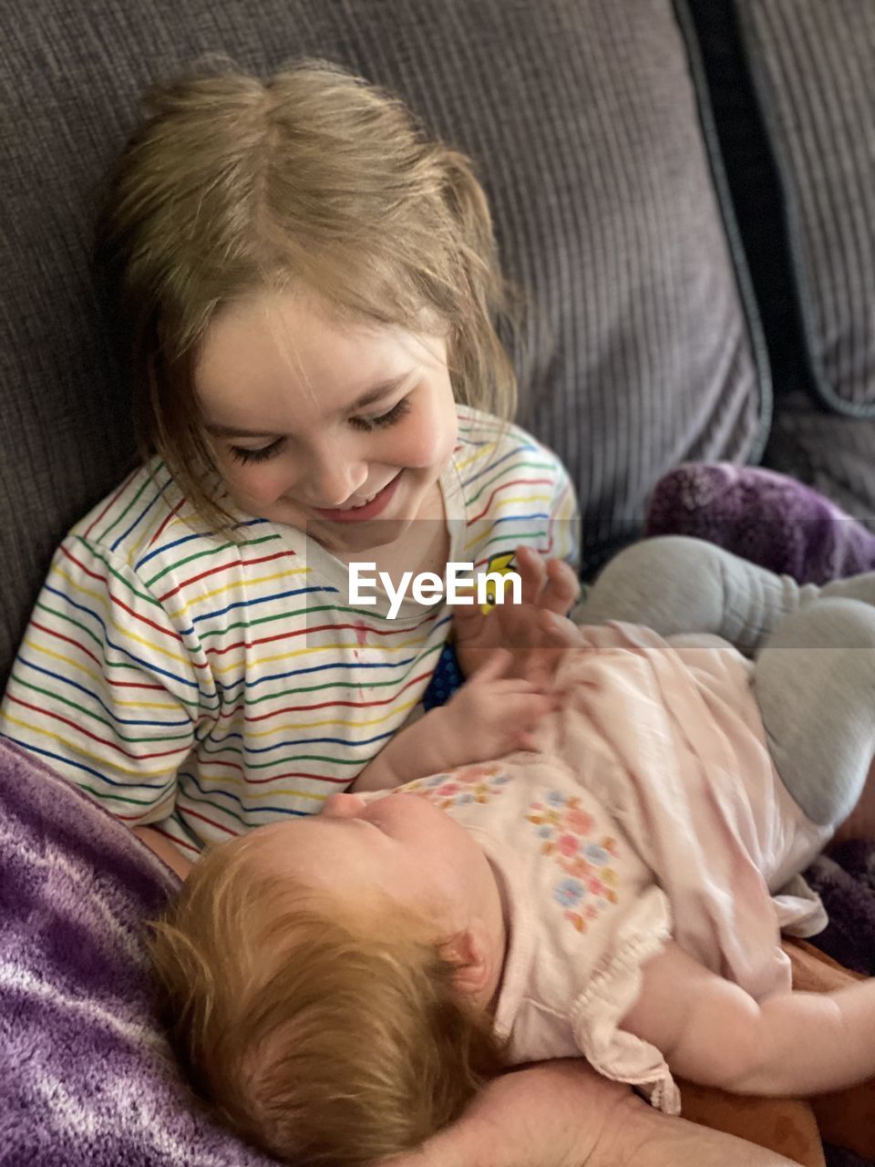 HIGH ANGLE VIEW OF SMILING GIRL LYING ON SOFA