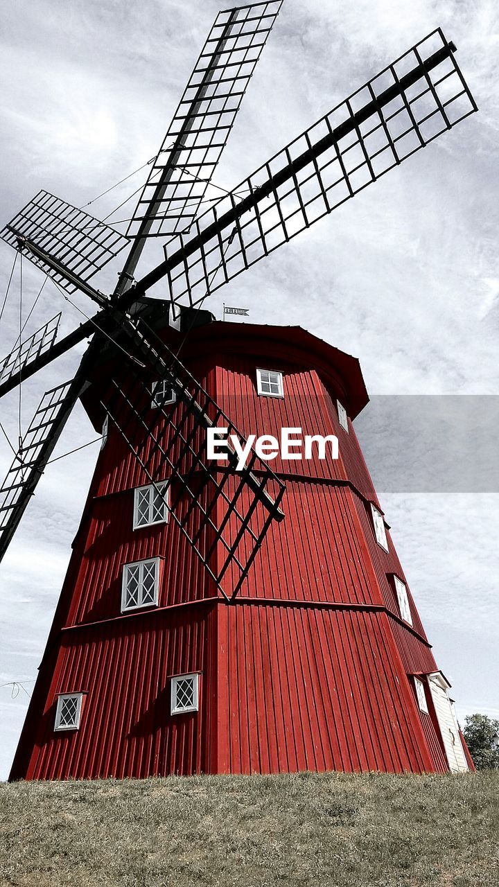 Low angle view of traditional windmill against cloudy sky