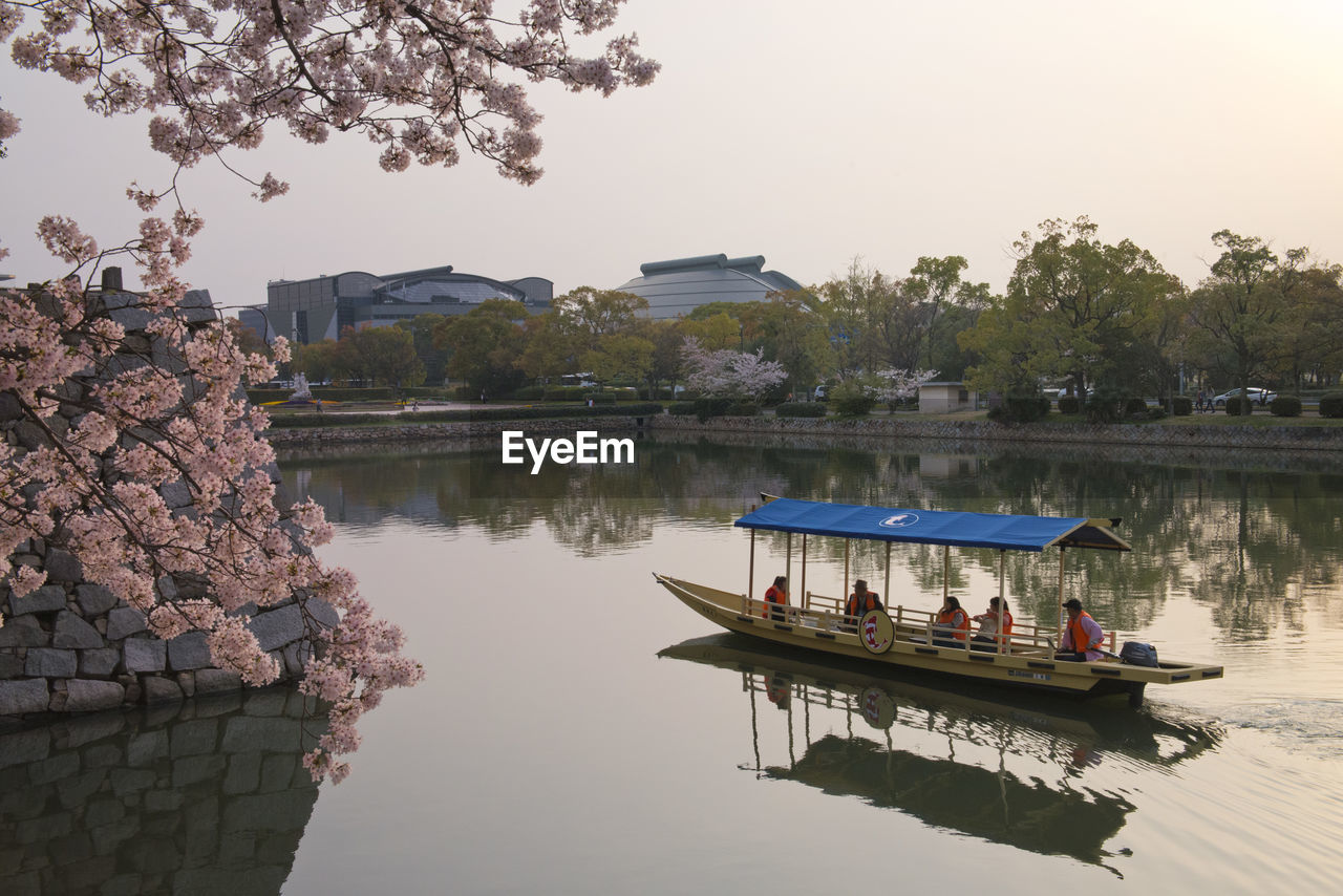 GROUP OF PEOPLE IN BOAT AGAINST LAKE