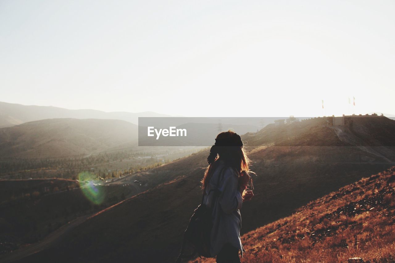 Side view of woman walking on mountain against clear sky