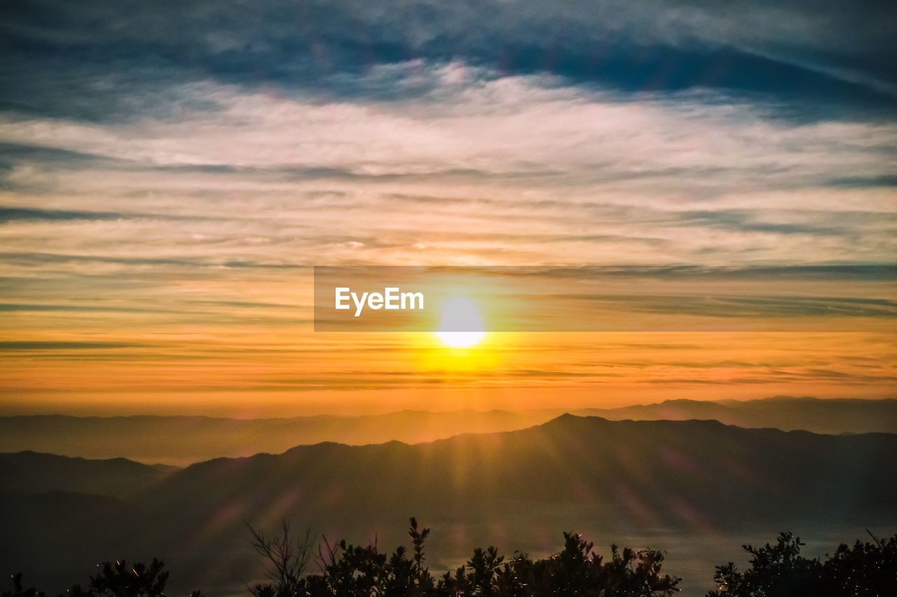 Scenic view of silhouette mountains against orange sky