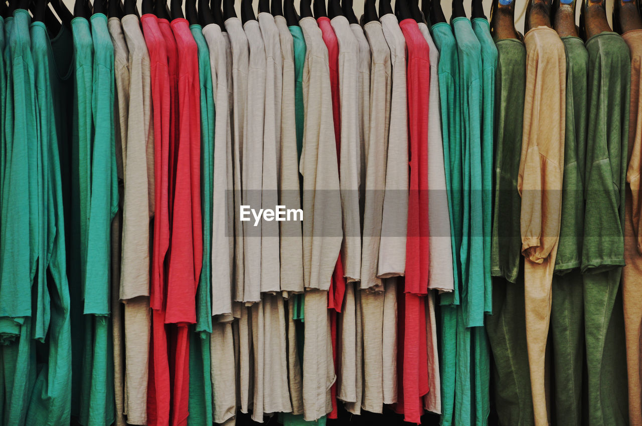 variation, multi colored, clothing, retail, hanging, large group of objects, store, no people, in a row, shopping, fashion, coathanger, abundance, business, textile, for sale, arrangement, side by side, rack, market, room, order, business finance and industry, backgrounds, small business, indoors, sale, clothes rack, full frame, retail display, collection, clothing store, consumerism, market stall, still life