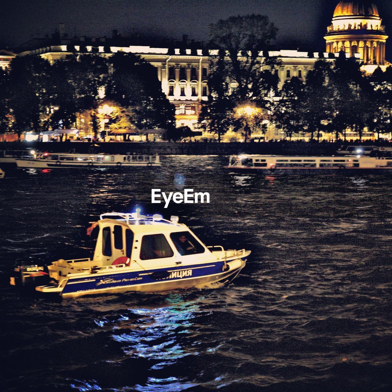 BOATS IN RIVER BY ILLUMINATED BUILDINGS IN CITY