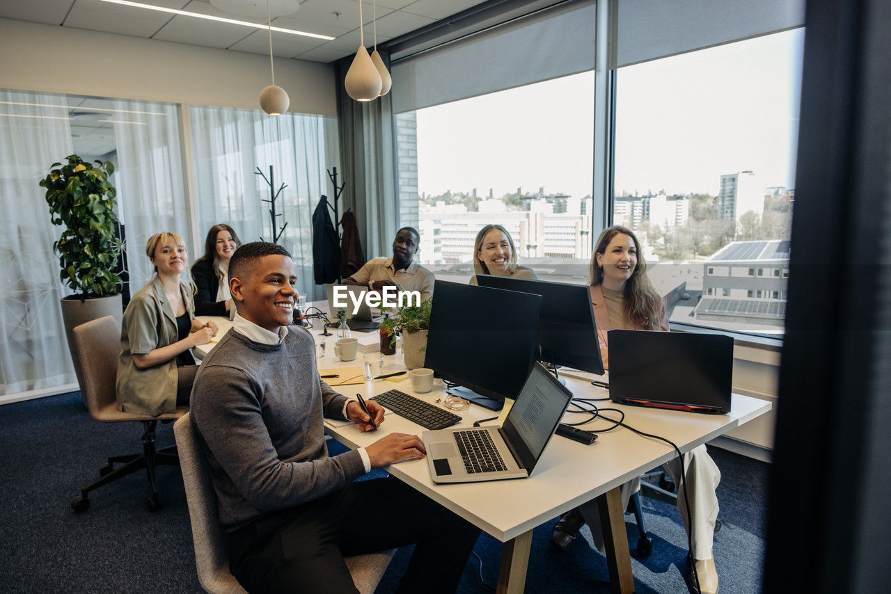 Smiling male and female business colleagues during video conference in coworking office