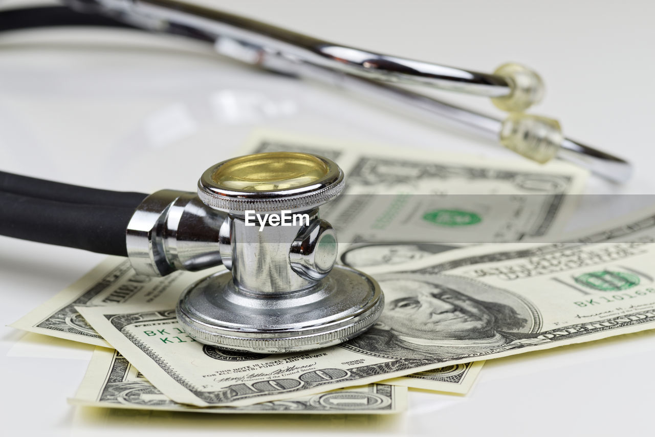 Close-up view of stethoscope and american dollars on white background