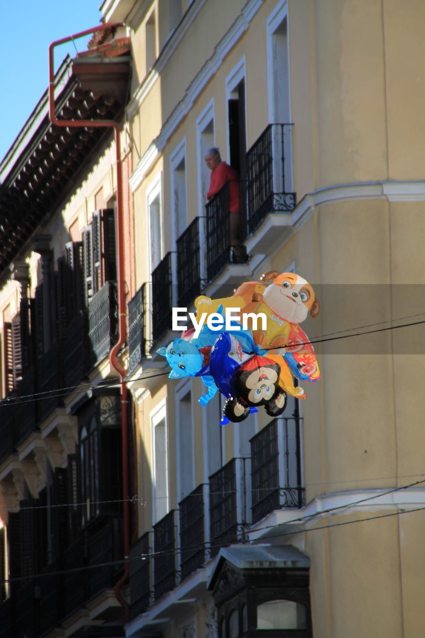 LOW ANGLE VIEW OF MULTI COLORED UMBRELLAS IN CITY