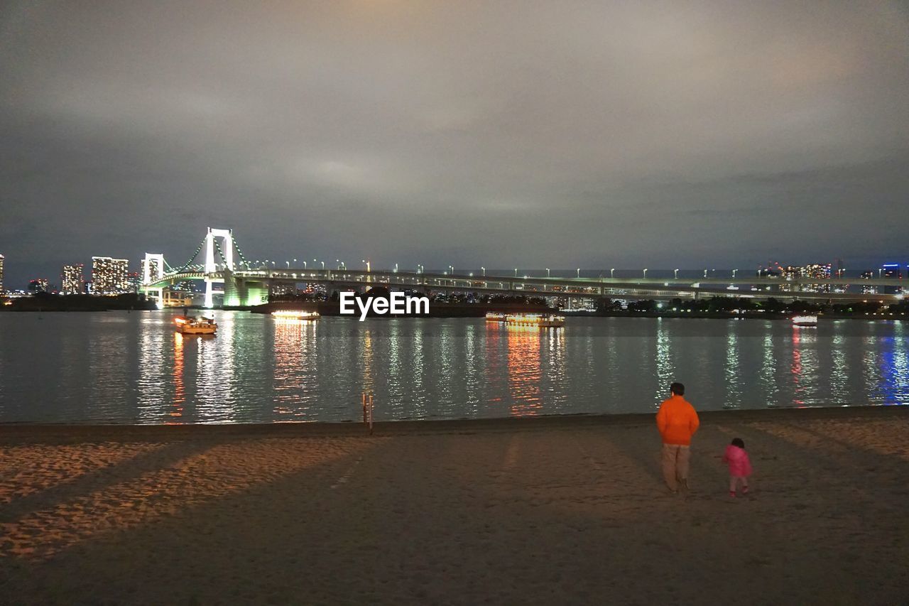 WOMAN STANDING IN ILLUMINATED CITY AT NIGHT