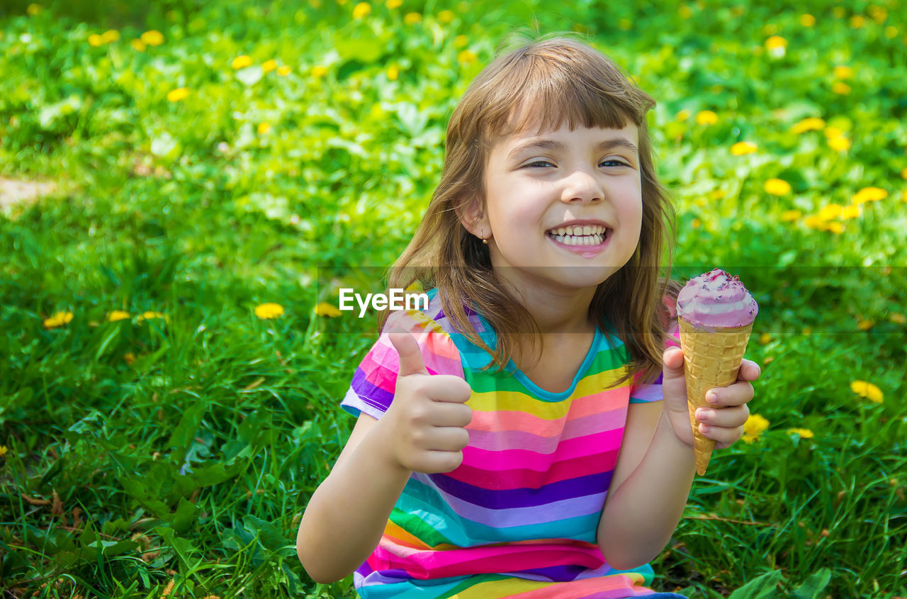 child, childhood, smiling, happiness, women, grass, summer, food and drink, plant, food, female, portrait, one person, sweet food, emotion, nature, frozen food, sweet, flower, cheerful, enjoyment, cute, freshness, ice cream, toddler, front view, person, looking at camera, holding, ice cream cone, fun, leisure activity, cone, teeth, smile, innocence, dairy, flowering plant, meadow, hairstyle, eating, lawn, day, long hair, field, lifestyles, plain, joy, outdoors, carefree, casual clothing, land, frozen, human face, green, sitting, dessert, blond hair, positive emotion, sunlight