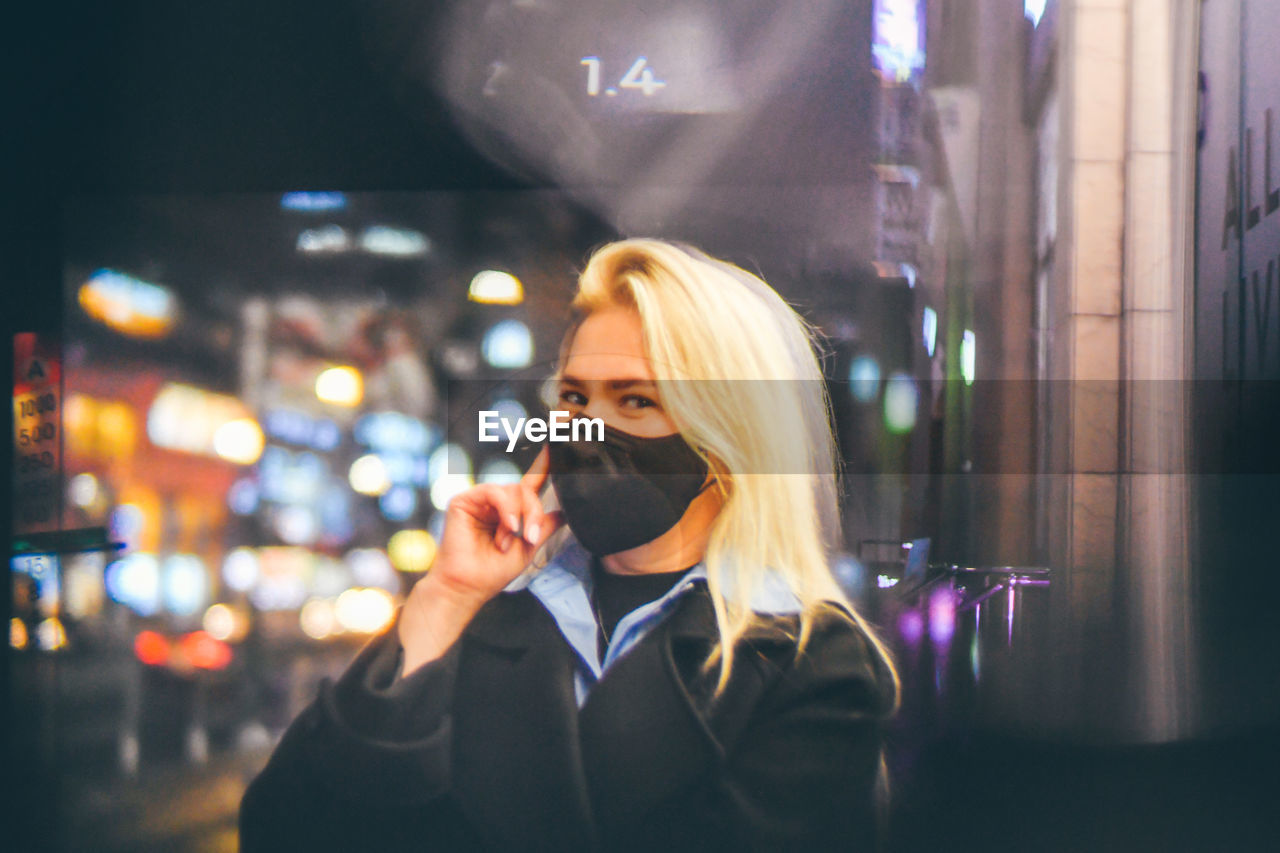 Portrait of smiling woman wearing mask talking on phone outdoors