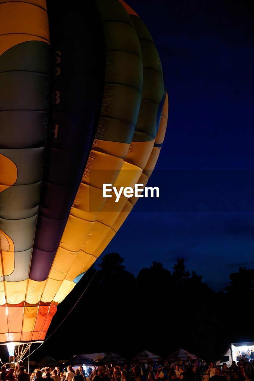 low angle view of illuminated hot air balloons against sky at night