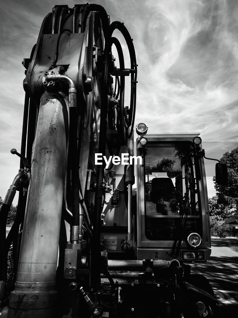 Close-up of construction machinery on road against cloudy sky