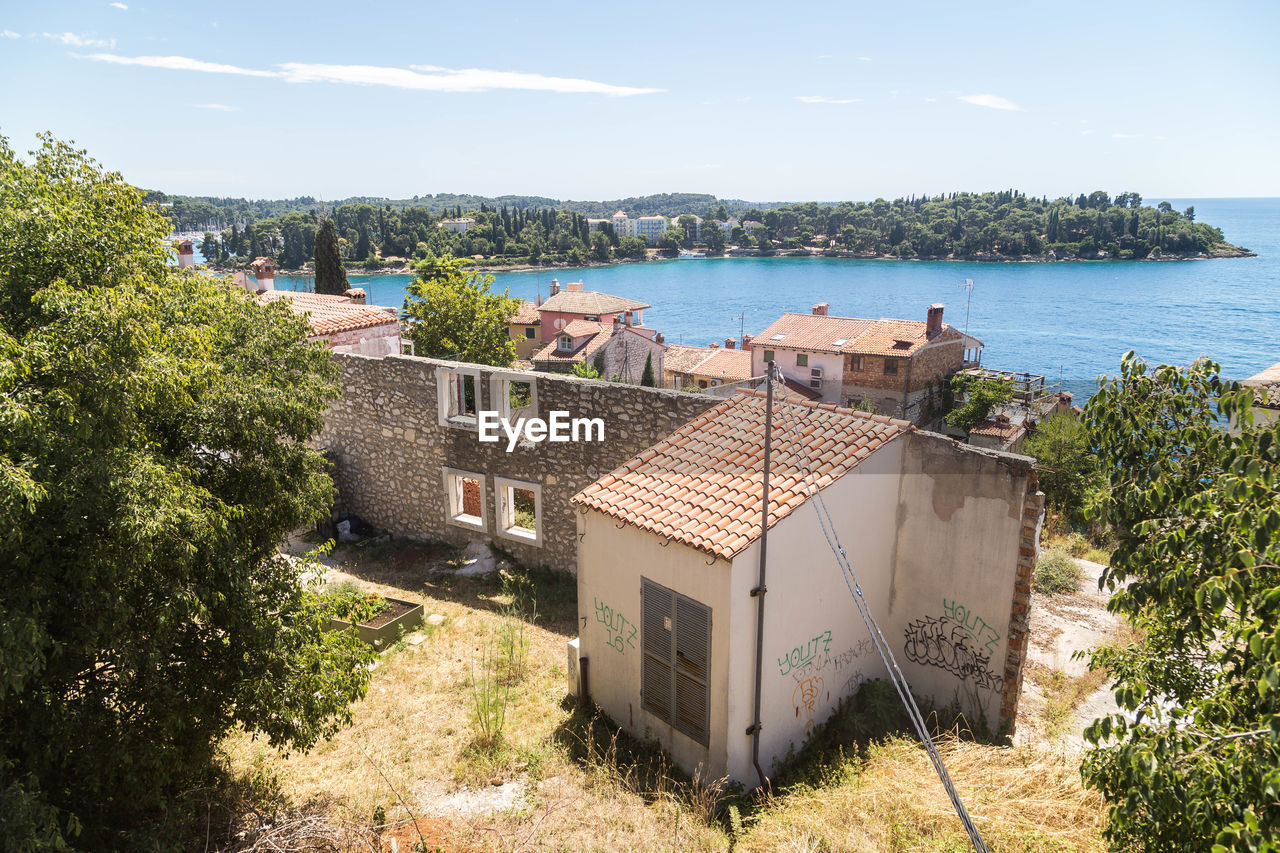 HIGH ANGLE VIEW OF HOUSES AND BUILDINGS BY SEA AGAINST SKY