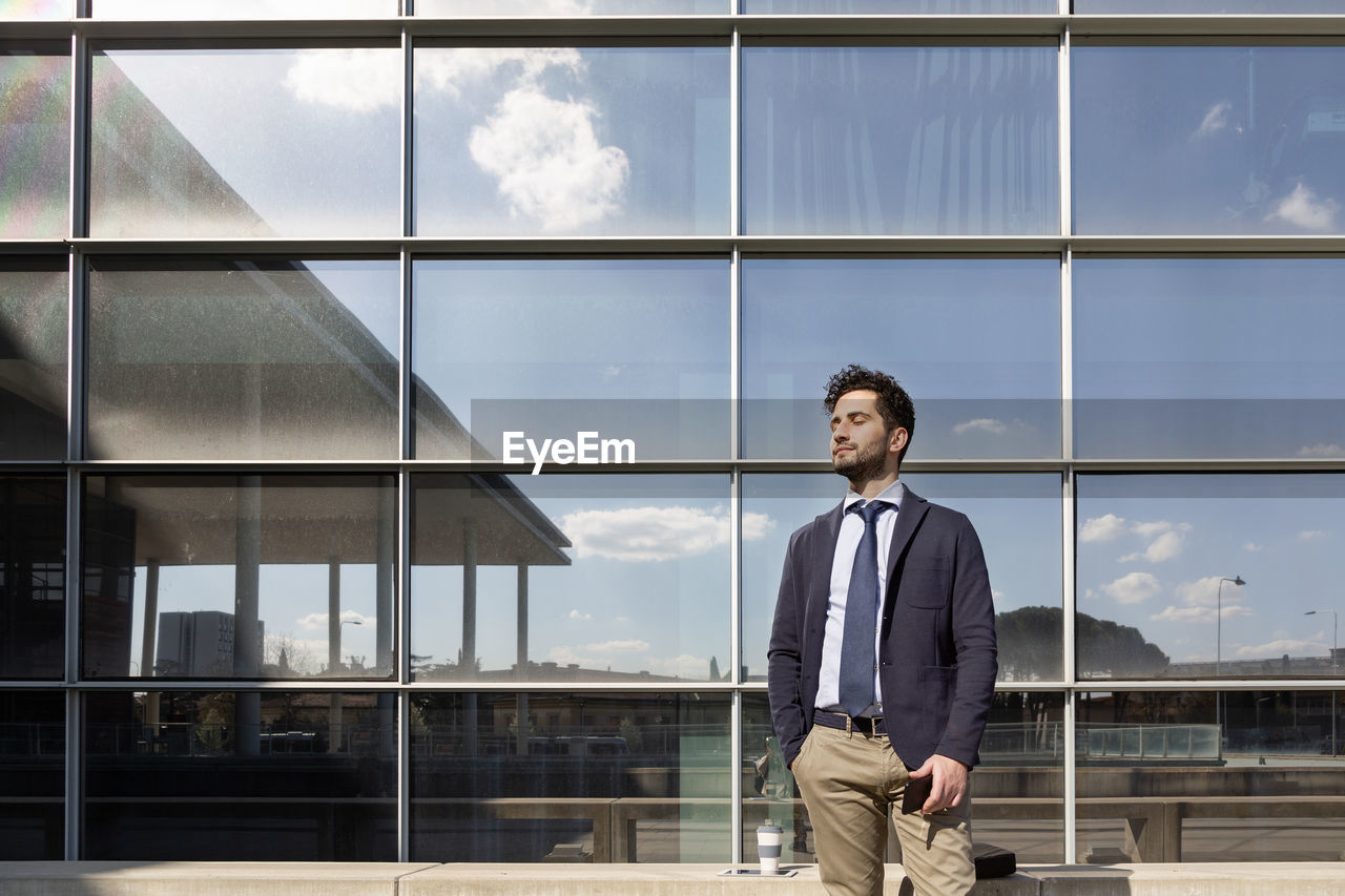 Mid adult male entrepreneur standing with eyes closed on sunny day