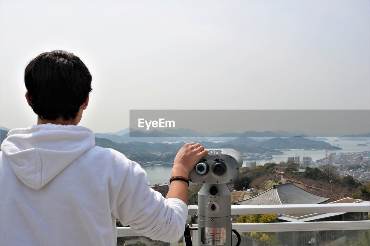 Rear view of boy looking at landscape against clear sky