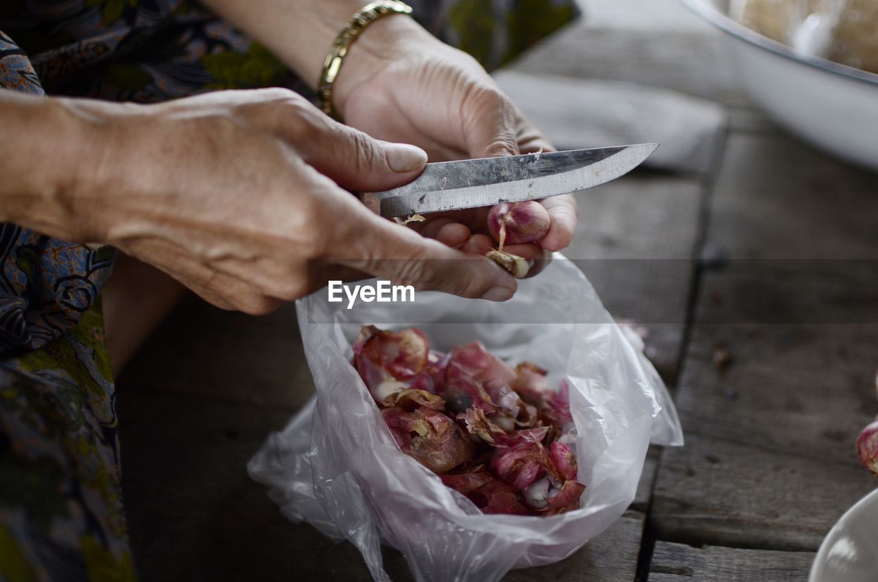 Cropped image of woman cutting onions on table at home