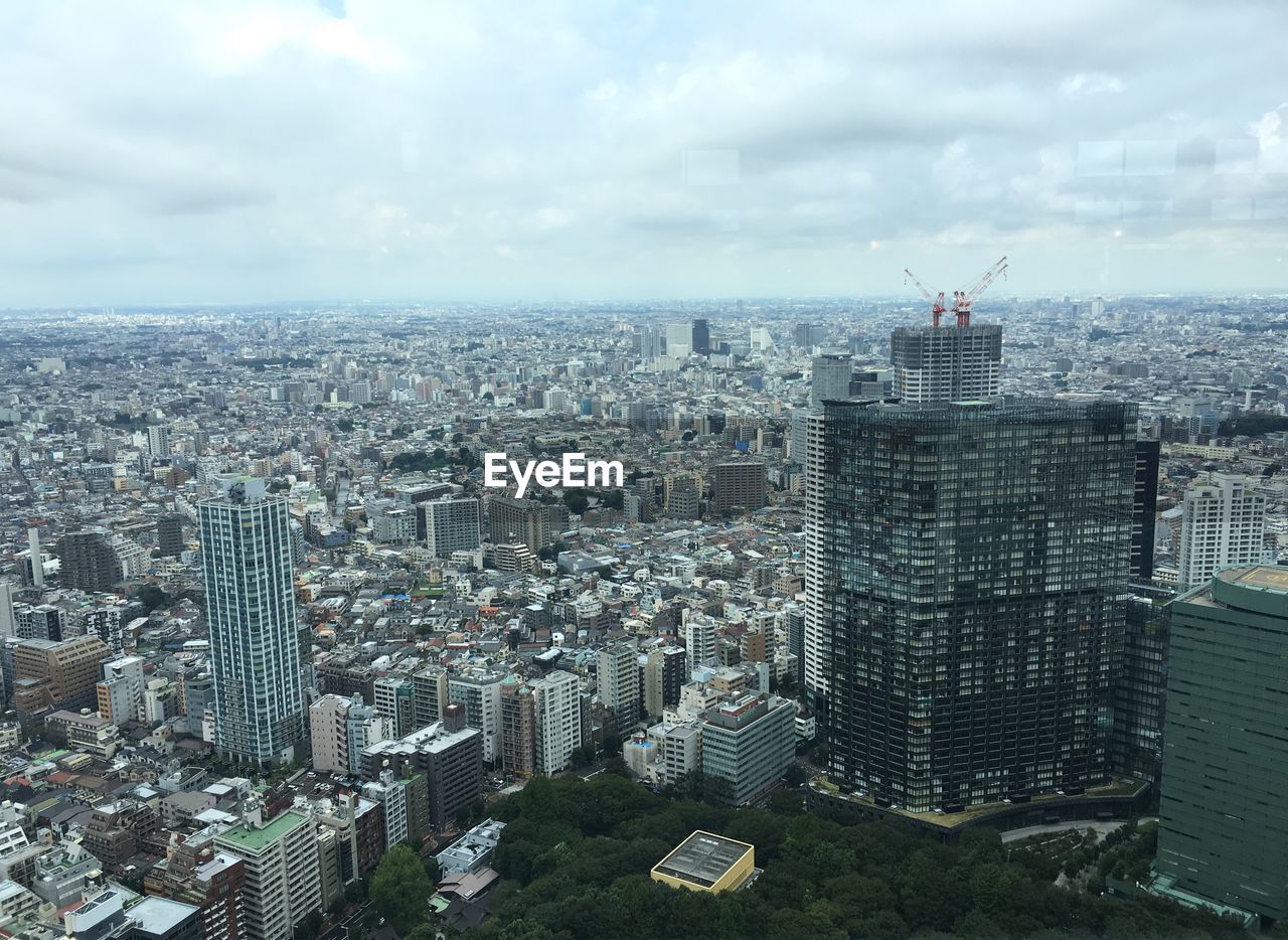 Aerial view of cityscape against cloudy sky