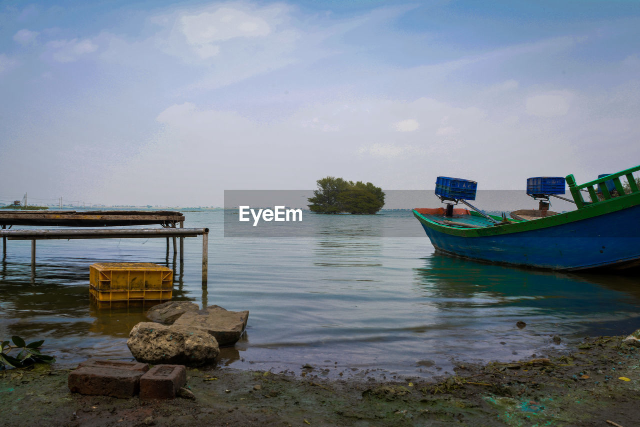 FISHING BOATS MOORED ON SEA AGAINST SKY