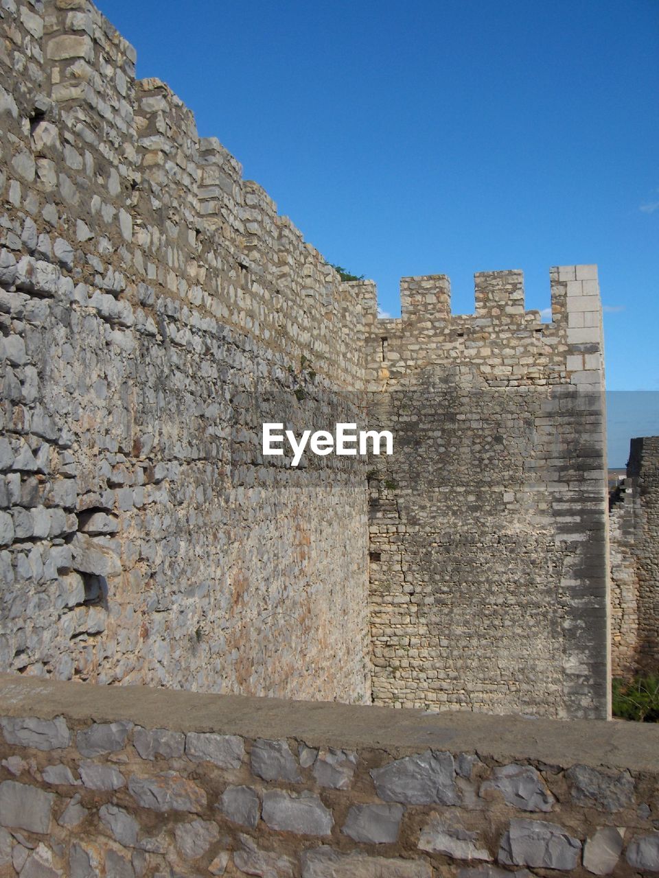 LOW ANGLE VIEW OF STONE WALL WITH OLD BUILDING