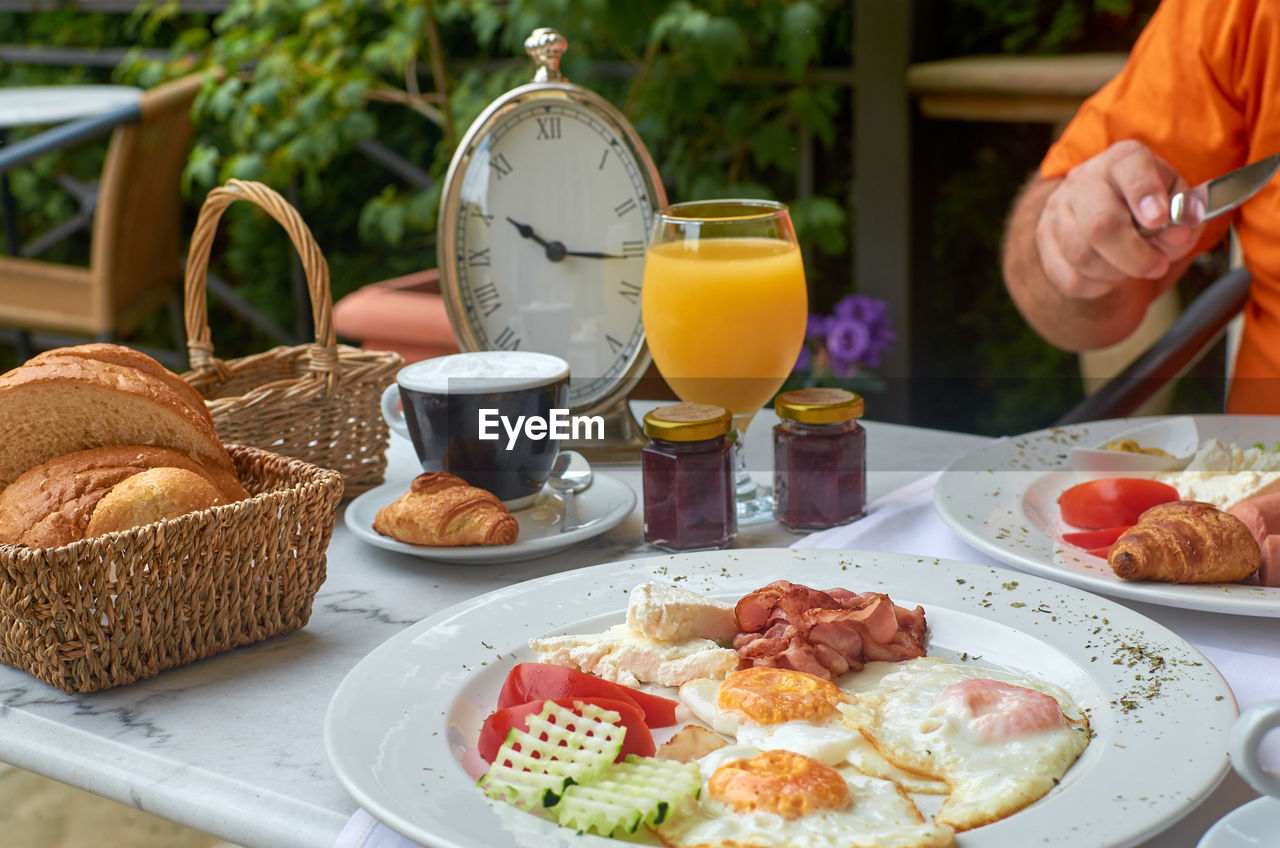Delicious breakfast served with a cup of cappuccino. there is a clock on a table showing 10.15 am
