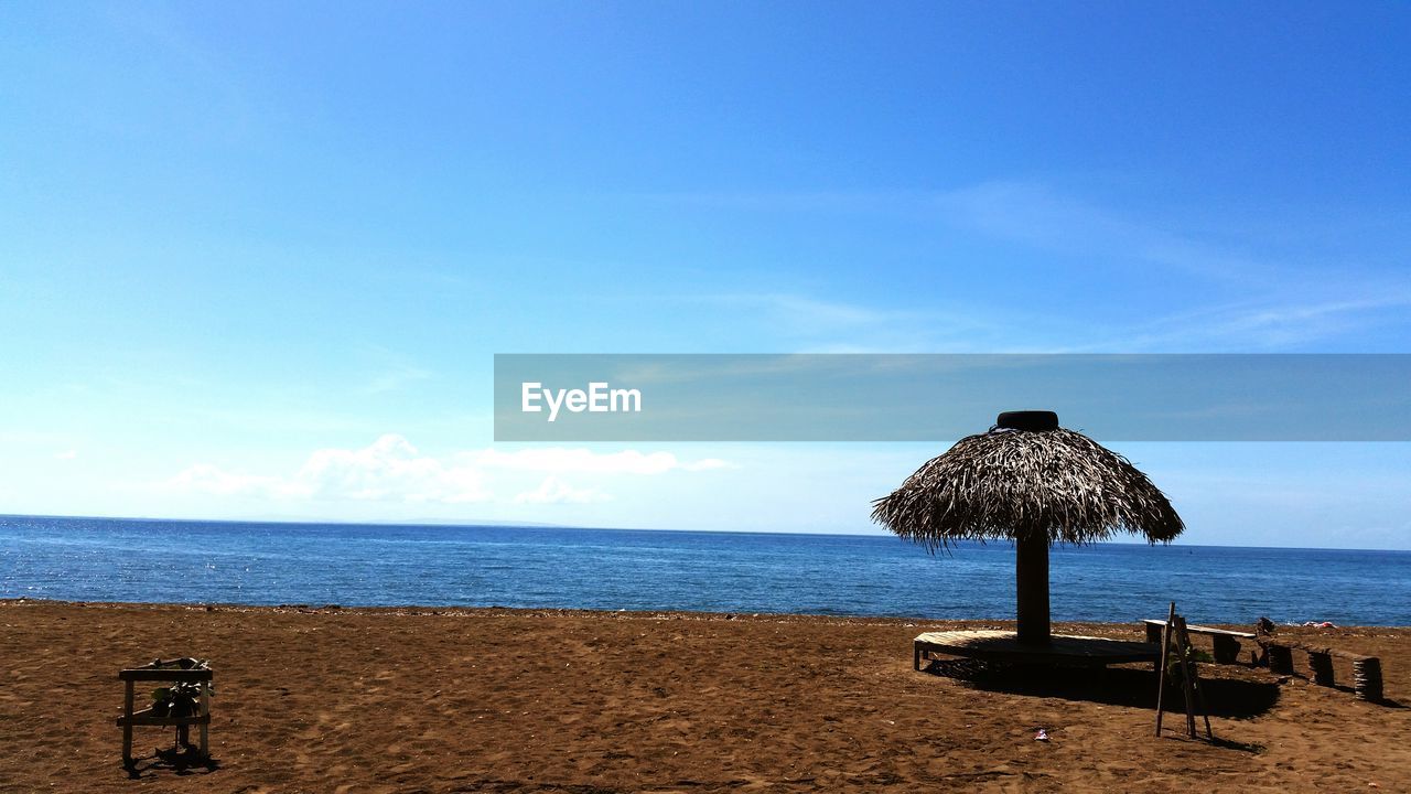 Thatched roof sunshade against blue sky on sunny day