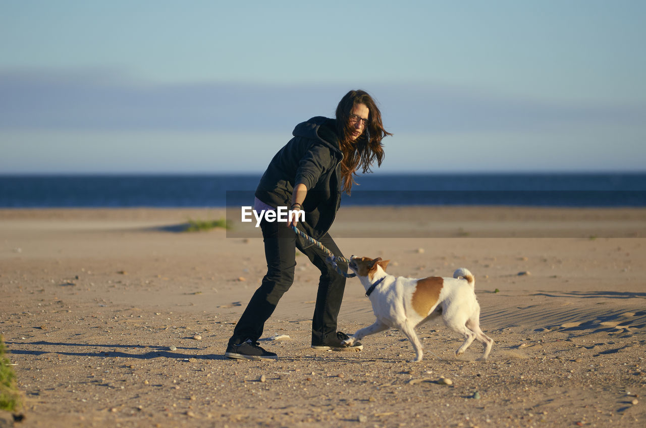 Full length of woman with dog at beach