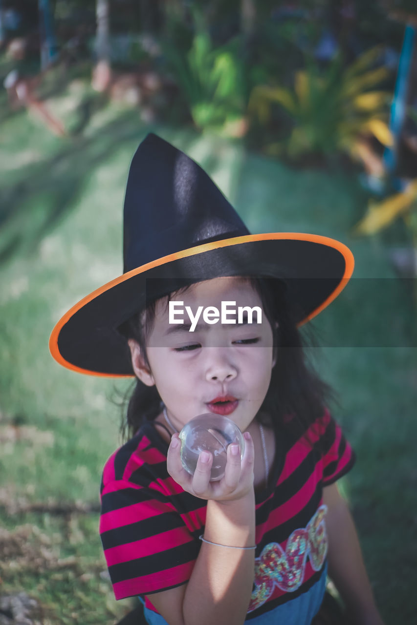 Girl wearing witch hat holding crystal ball