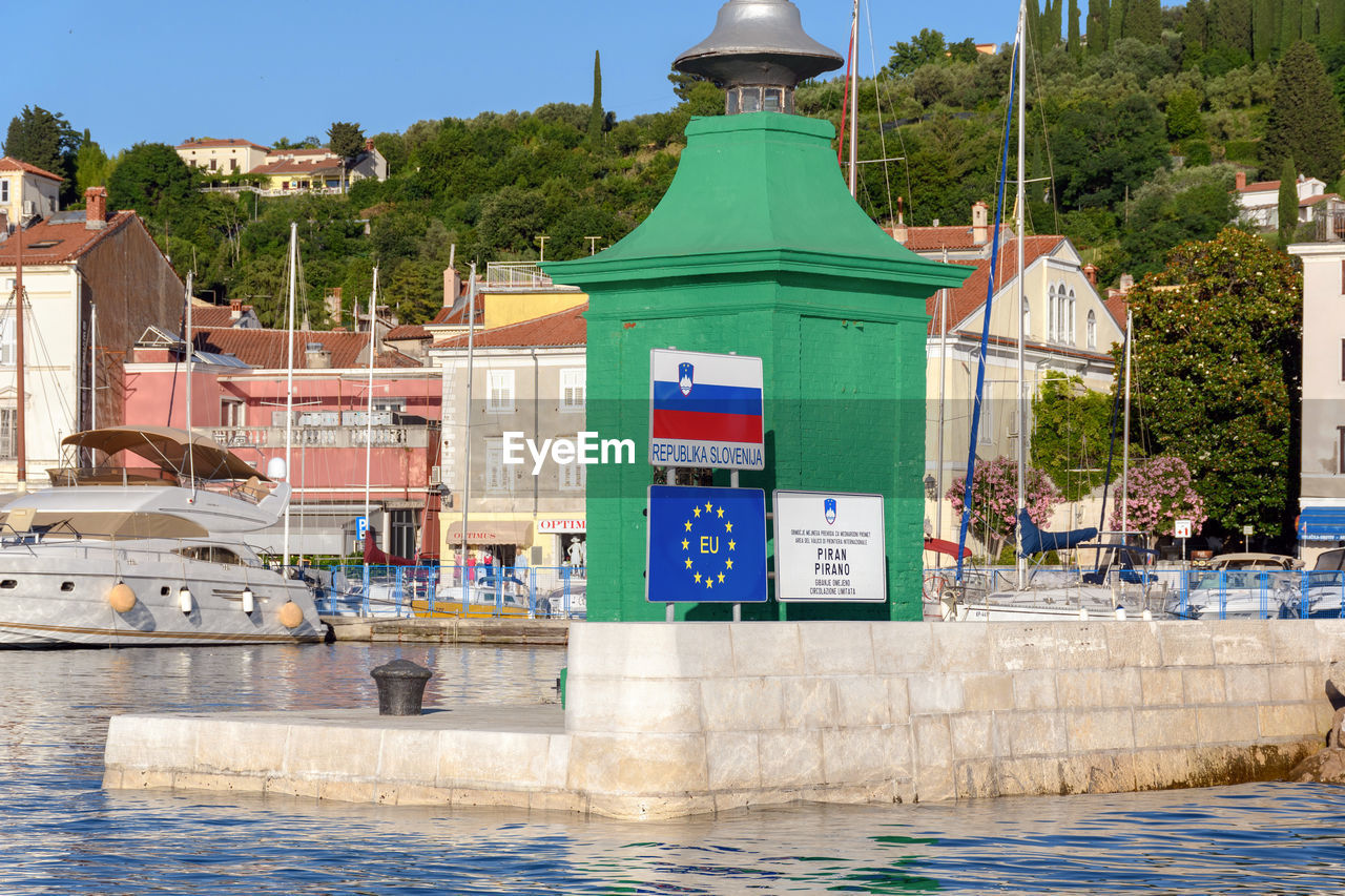 Border crossing sings in front of green lighthouse in port of piran in slovenia