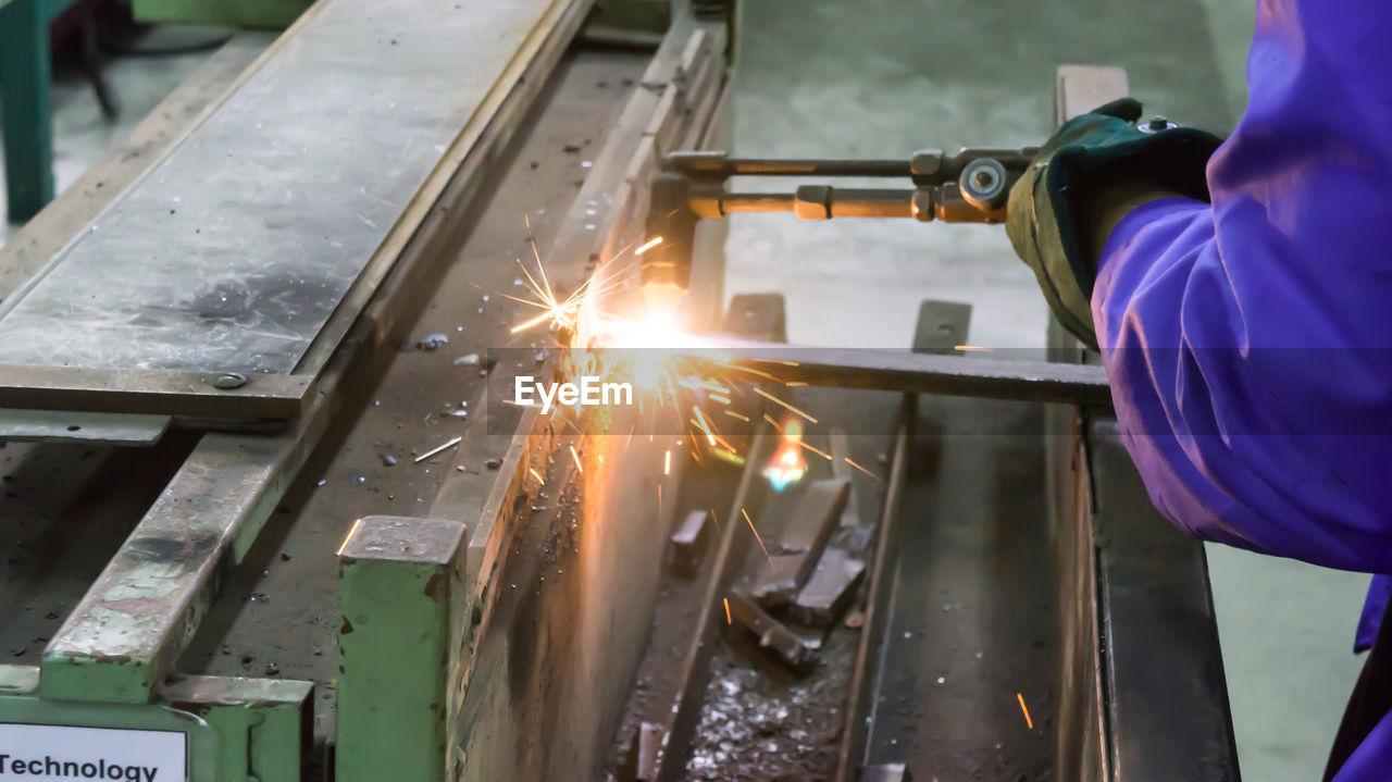 Midsection of man welding at factory