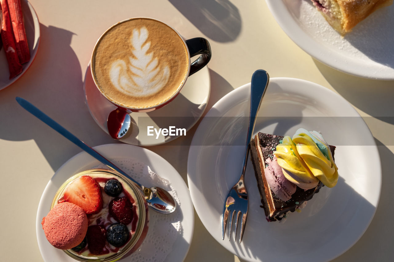 Desserts, cup of cappuccino with decorated foam on table, latte art, in cafe, on sunny day