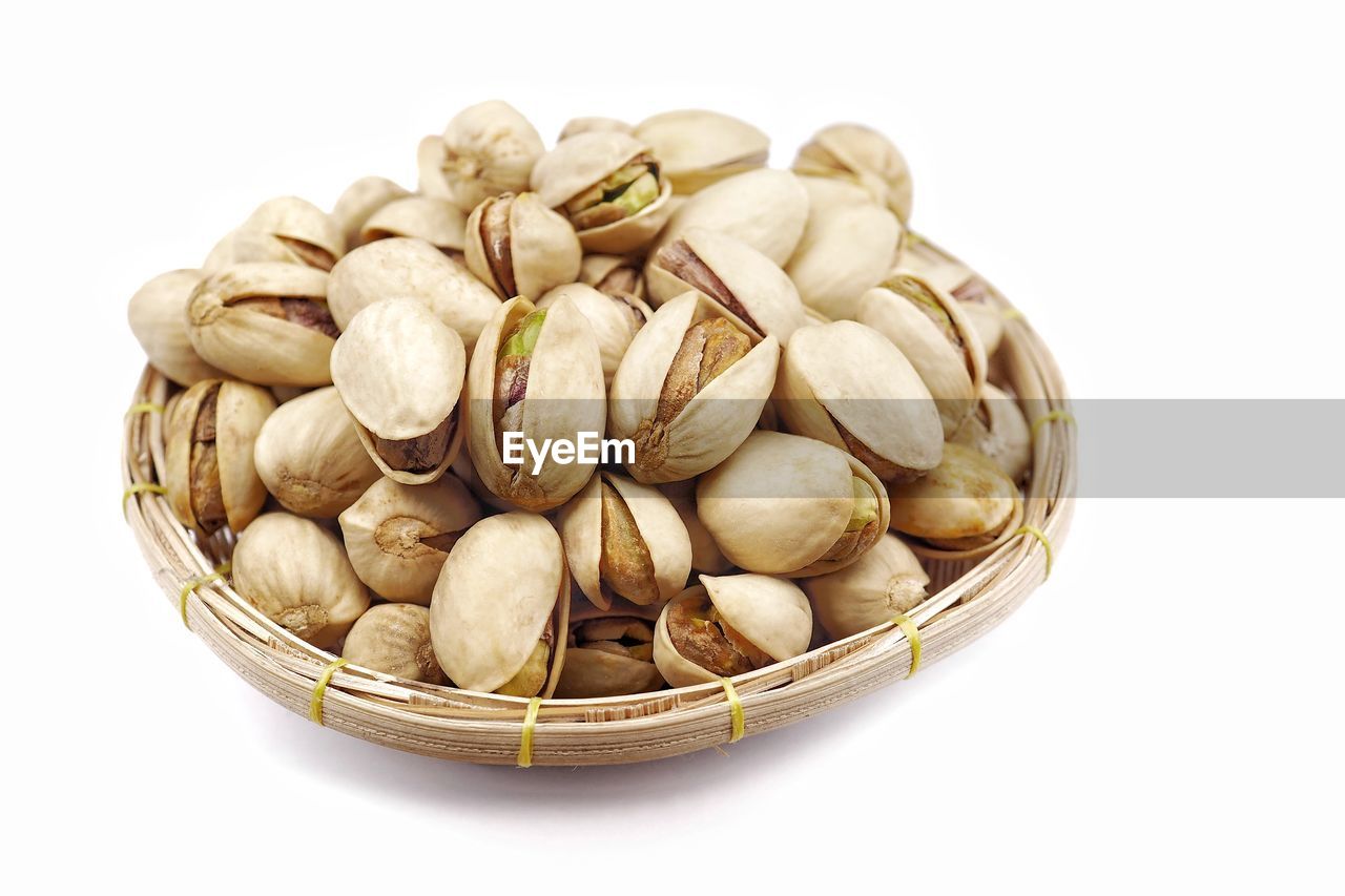 Close-up pistachio nuts in a basket selling with isolated white background.